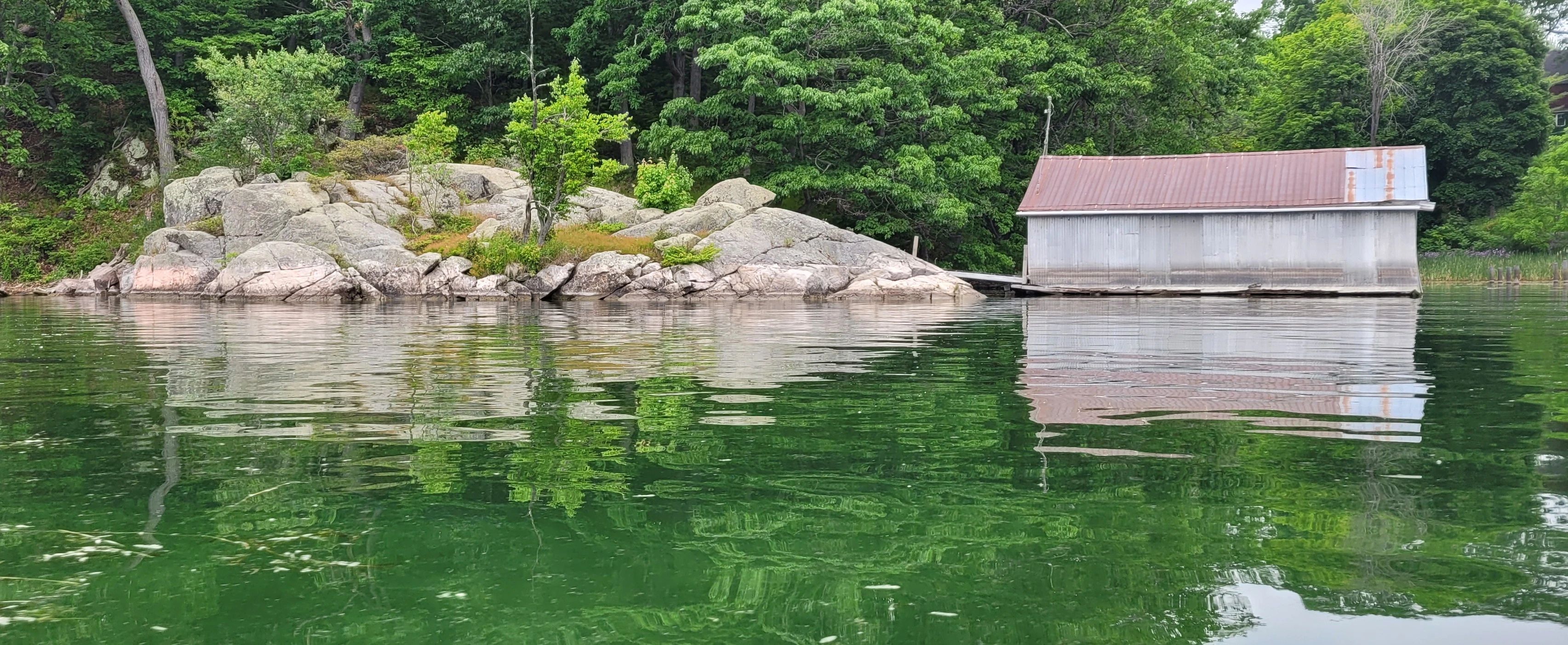KayaA boathouse and a rock reflecting over the water in the Thousand Islands in Ontario Canada